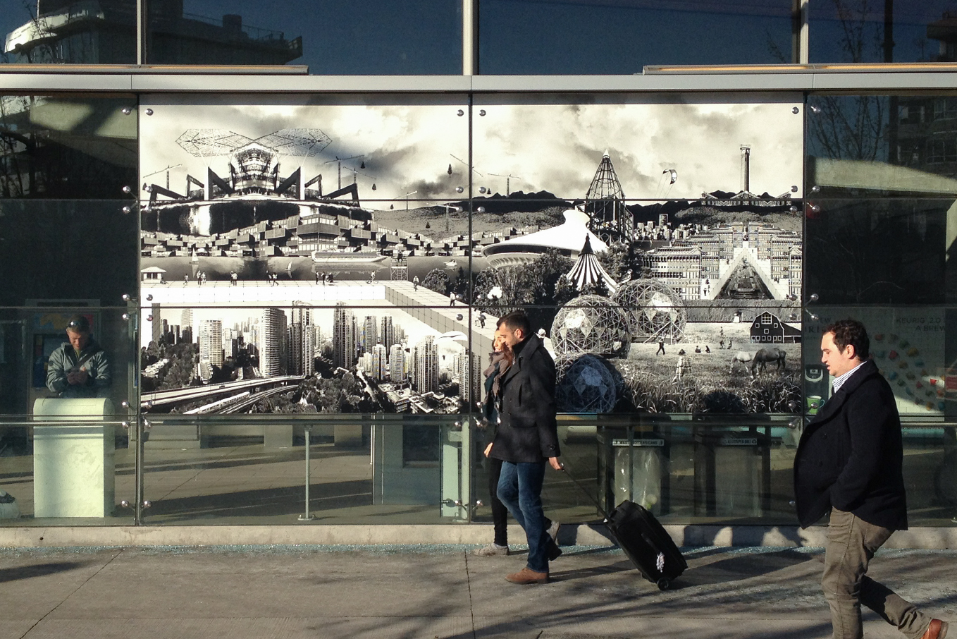 Pedestrians walking in front of the installed montage at Olympic Village Skytrain Station.