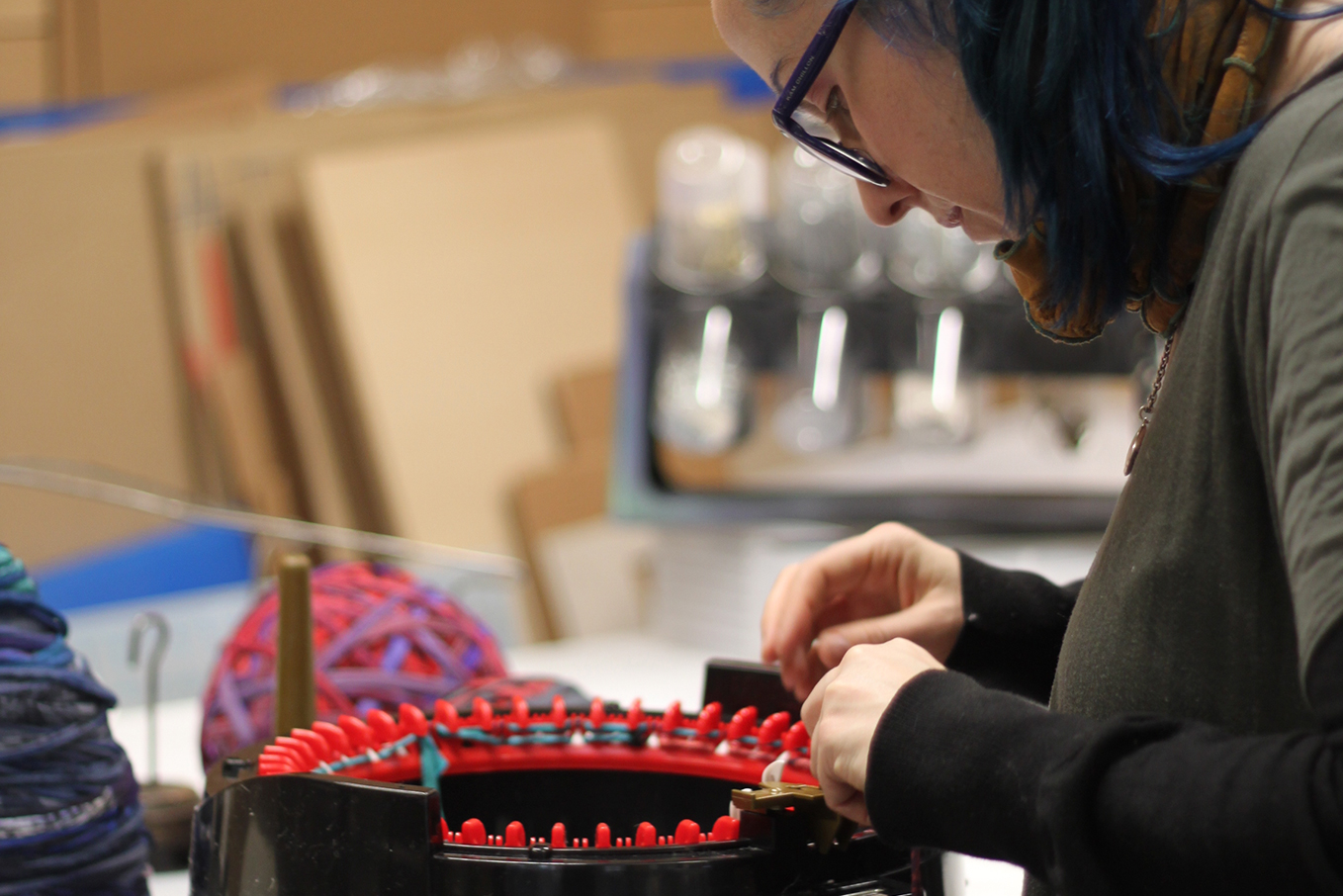 Photo of Katherine Soucie working on her piece at a table.