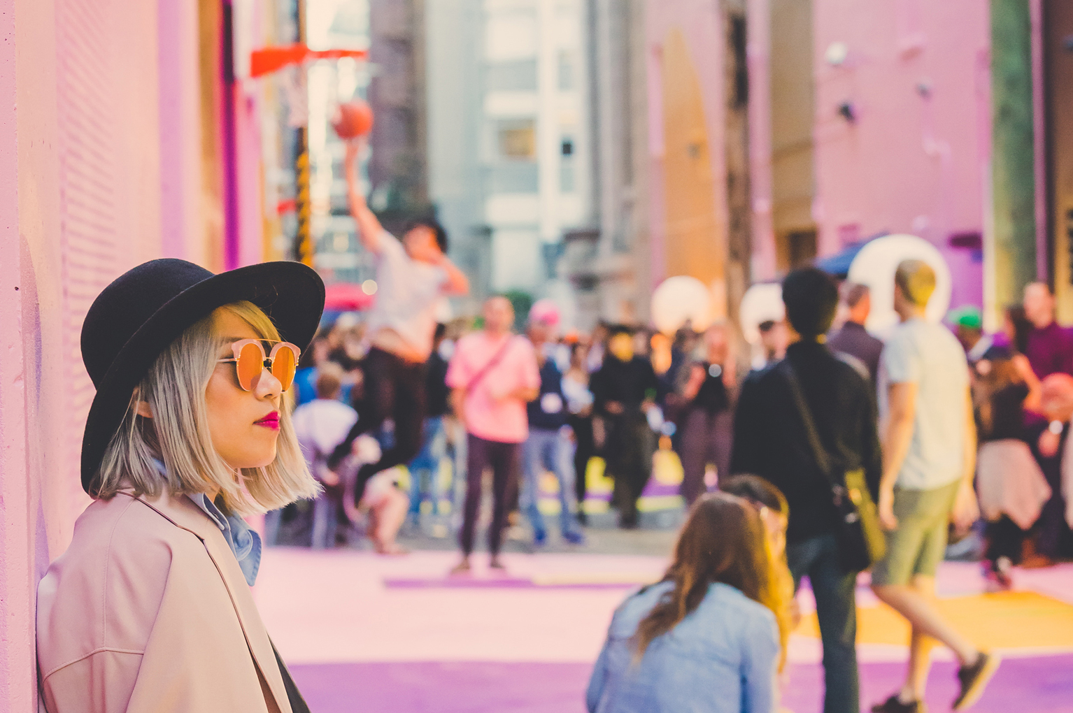 A girl in focus while a group of people are in the background playing basketball in Alley-Oop.