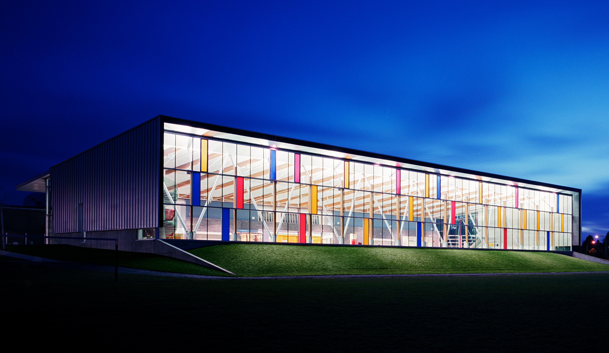 A photo of Killarney Community Pool at night. The building is internally lit against a dark sky.