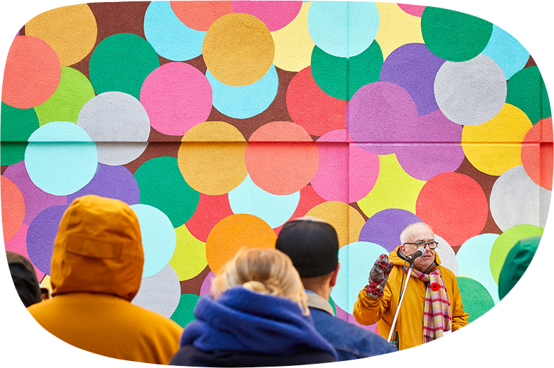 Michael Phair addressing the crowd in front of the confetti wall at the park that was named in his honour.