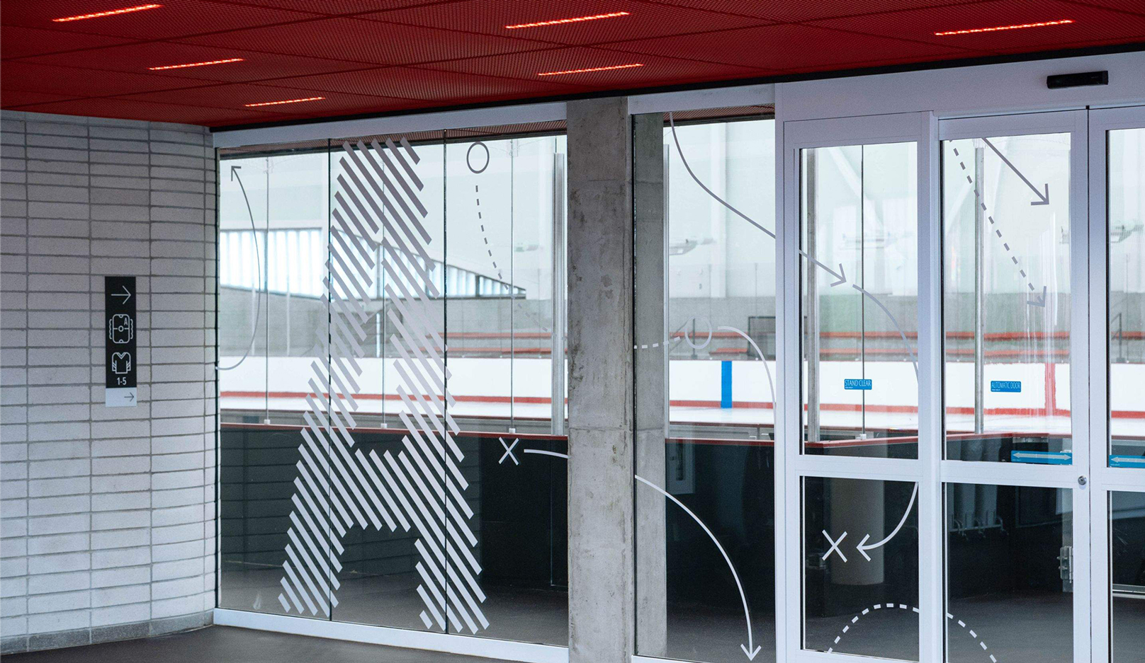A white line graphic of skating jesture and a large 'A' on the window into the ice rink.