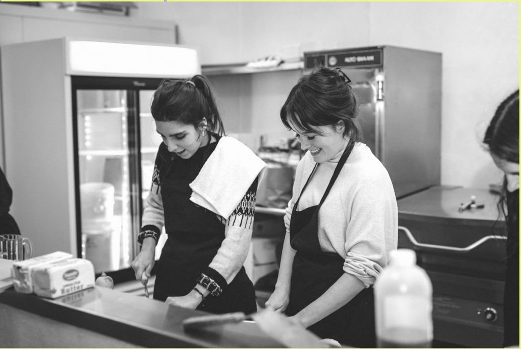 Two female hcma staff members volunteering in the kitchen at the Plenty of Plates event.