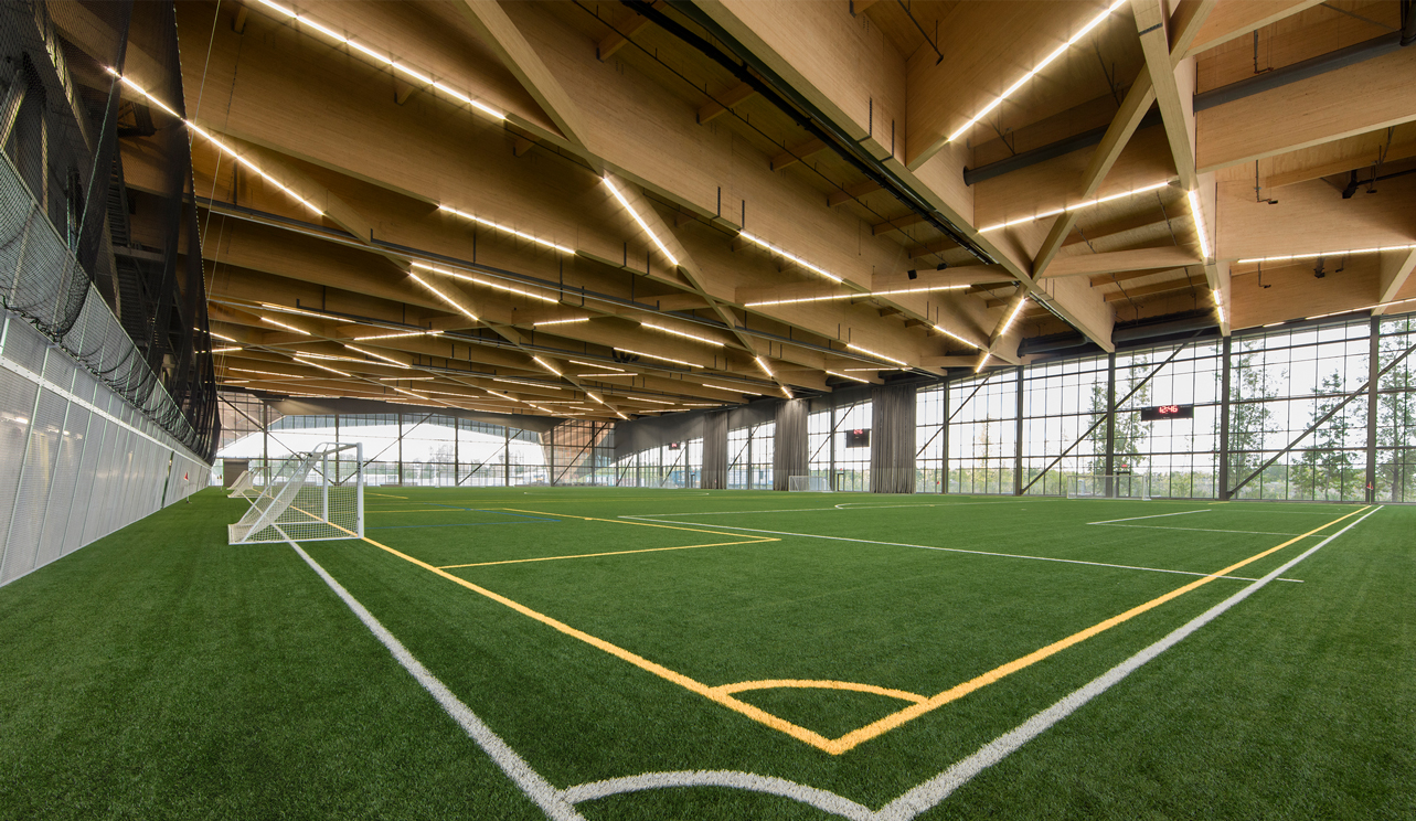 Stade de Soccer de Montreal indoor soccer pitch, its geometric CLT ceiling beams and integrated LED light strips.