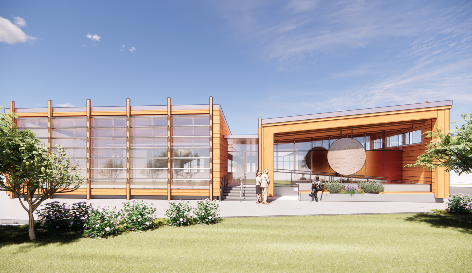 A digital rendering of the front perspective of the Sḵwx̱wú7mesh Elders Centre Expansion, featuring the building’s entryway. The exterior design of the building resembles the form and character of a traditional Coast Salish Longhouse. The glazed façade on the left side of the image looks into the new lounge space. The right side features a ramp to the entry, as well as an outdoor bench integrated with a location to feature Sḵwx̱wú7mesh art.