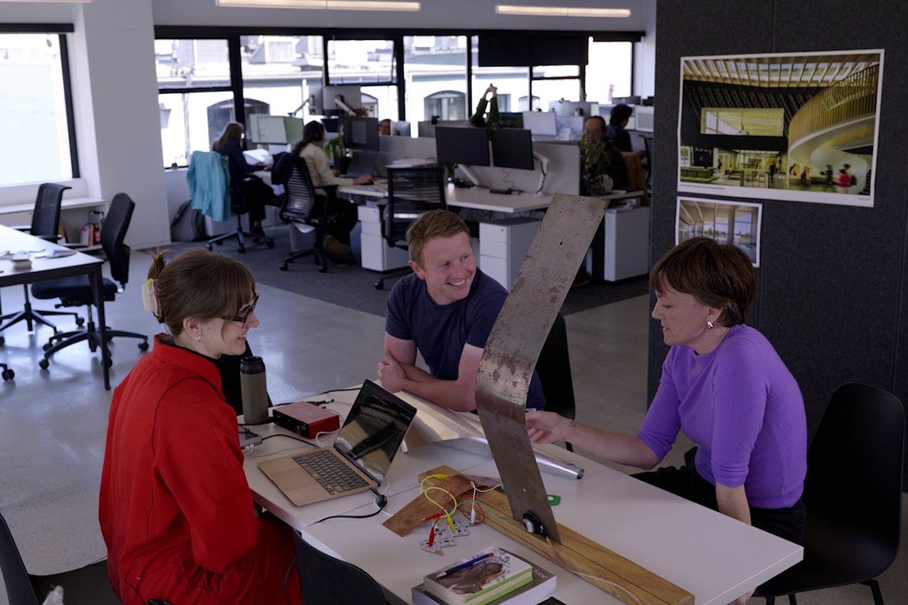 Edie interacting with hcma staff. They all sit at a table together along with the sculpture.