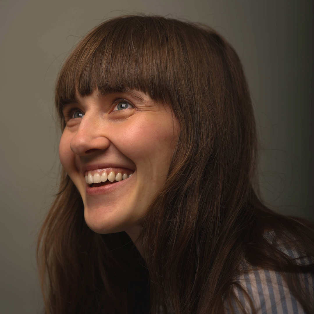 Headshot of Edie--they are smiling and looking off into the distance.