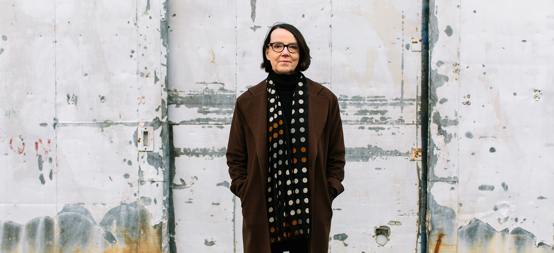 Lifestyle headshot of Karen Marler standing in front of a white, textured wall.