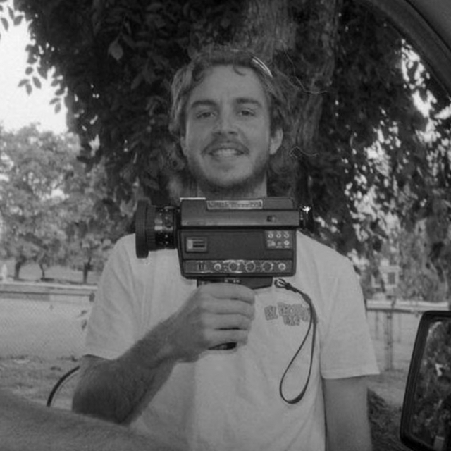Black and white, grainy film photo of Isaac holding an old video camera.